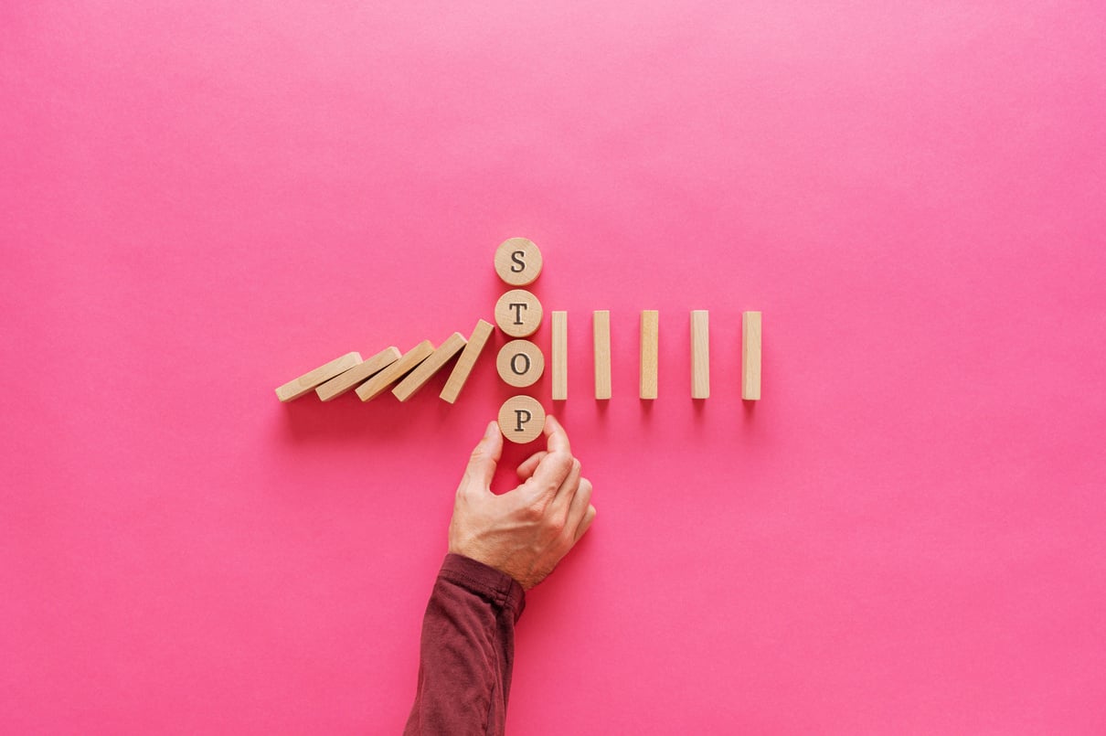 Male Hand Interrupting Falling Dominos